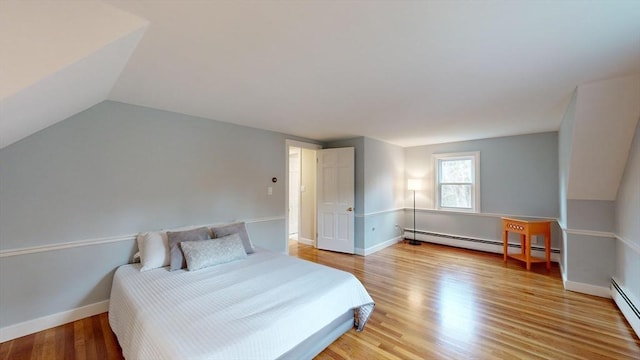 bedroom with lofted ceiling, light hardwood / wood-style flooring, and baseboard heating