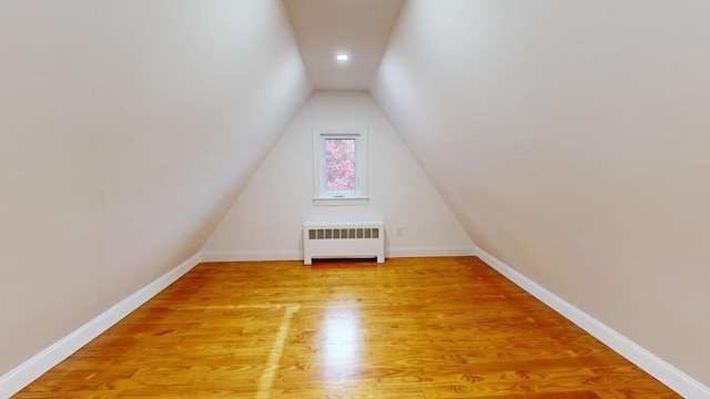 bonus room featuring radiator, light hardwood / wood-style floors, and vaulted ceiling