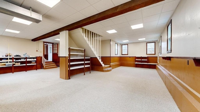 basement featuring a drop ceiling and light colored carpet