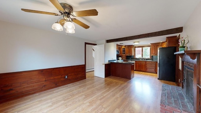 kitchen featuring a center island, stainless steel appliances, a brick fireplace, light hardwood / wood-style flooring, and decorative backsplash