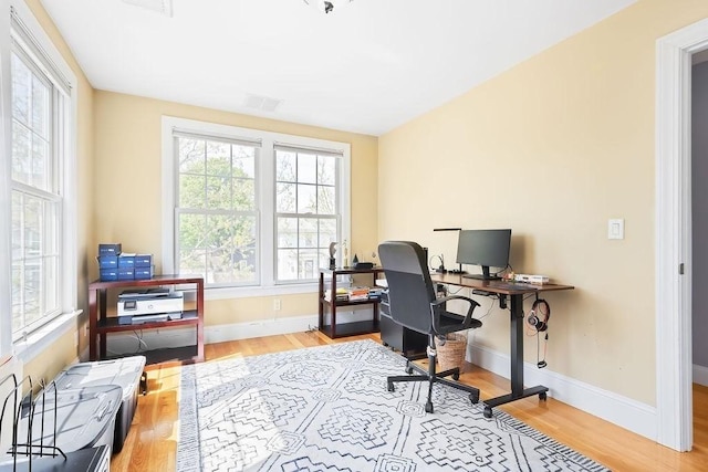 office space with healthy amount of natural light, wood finished floors, and baseboards