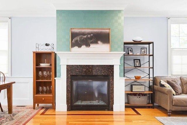 living room with wood finished floors, ornamental molding, and a large fireplace