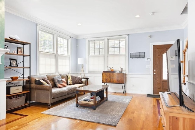 living room with crown molding, light wood finished floors, a wainscoted wall, and a decorative wall