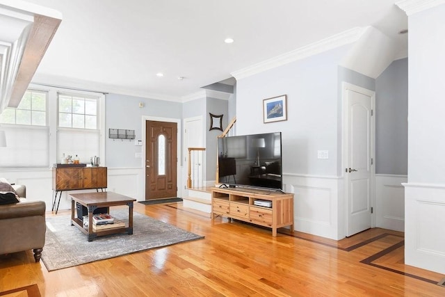 living area featuring ornamental molding, light wood-style floors, a decorative wall, and a wainscoted wall