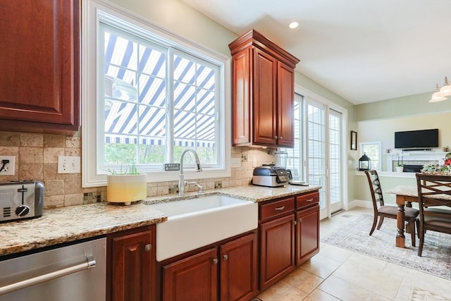 kitchen featuring stainless steel dishwasher, a sink, healthy amount of natural light, light tile patterned flooring, and recessed lighting