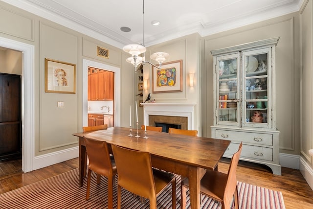 dining room featuring ornamental molding, sink, and wood-type flooring