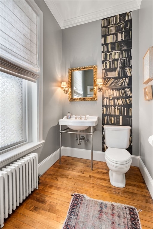 bathroom featuring ornamental molding, radiator, hardwood / wood-style flooring, sink, and toilet