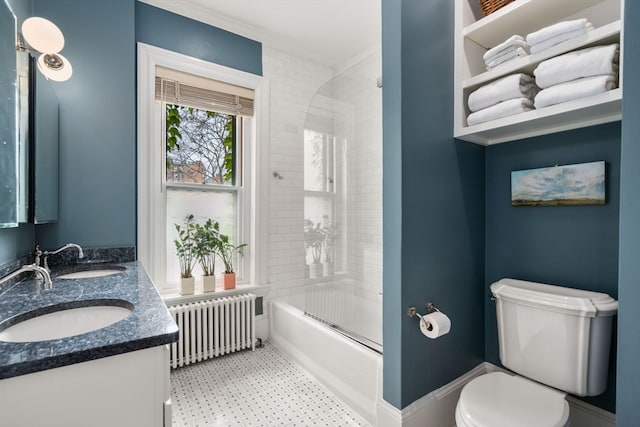 full bathroom with tile flooring, double sink vanity, tiled shower / bath combo, radiator heating unit, and toilet