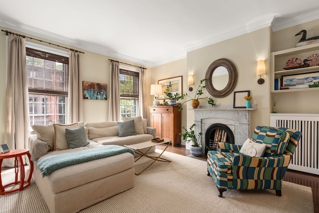 living room with a premium fireplace, crown molding, radiator, and hardwood / wood-style floors