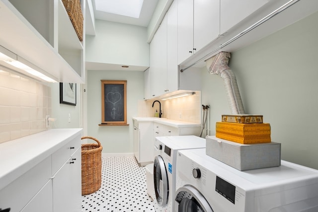 laundry room with independent washer and dryer, light tile flooring, sink, a skylight, and cabinets