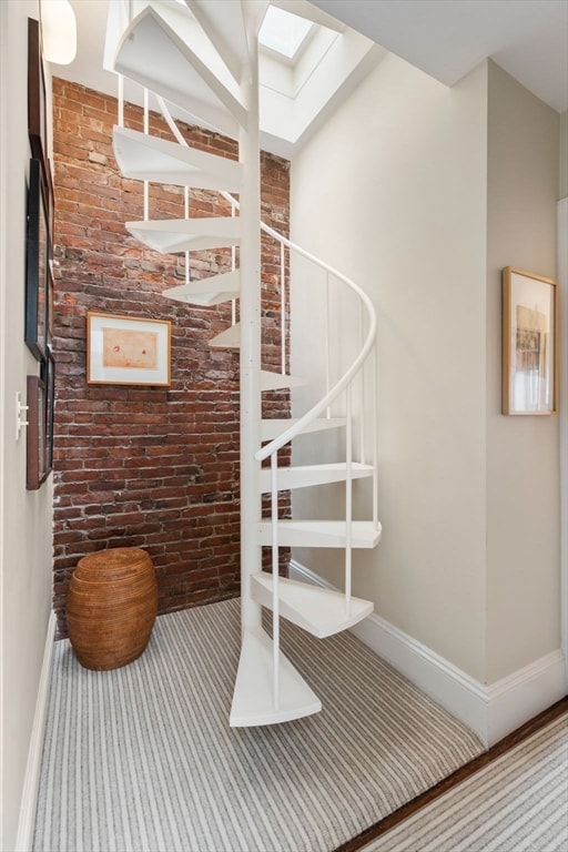 staircase with a skylight and brick wall