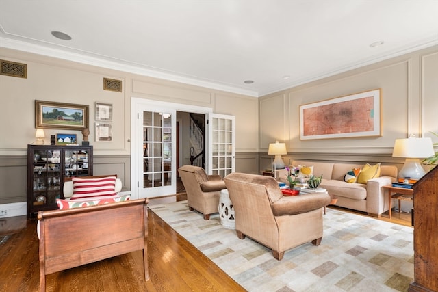 living room with hardwood / wood-style floors, ornamental molding, and french doors