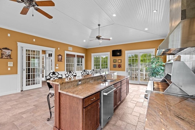 33 Moniz Dr, Westport, MA 02790 - kitchen with dishwasher, a ceiling fan, a breakfast bar area, stone tile floors, and a wainscoted wall