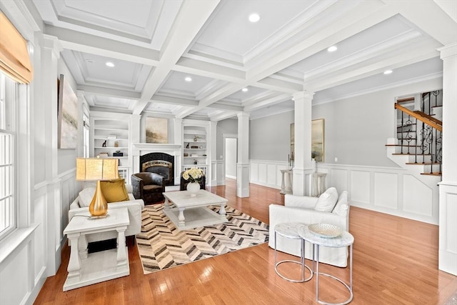 33 Moniz Dr, Westport, MA 02790 - living area featuring ornate columns, a decorative wall, a glass covered fireplace, wood finished floors, and beamed ceiling