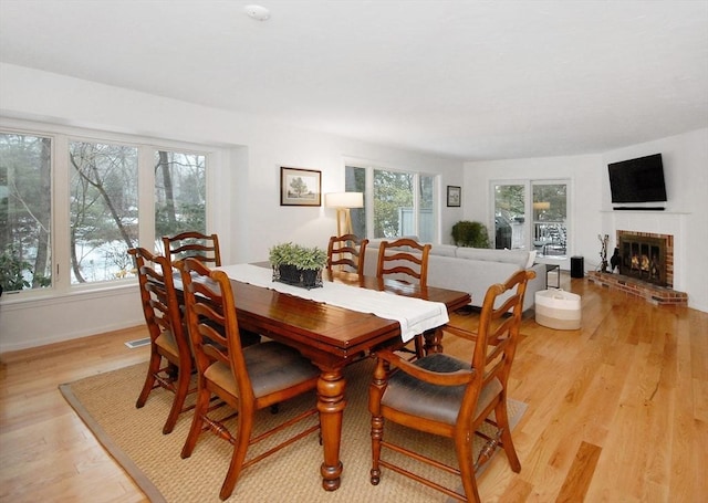 dining room with a fireplace, plenty of natural light, and light hardwood / wood-style floors