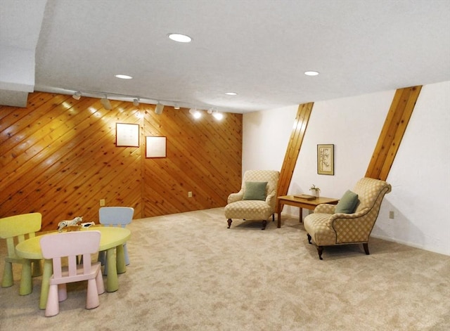 living area featuring light carpet, wooden walls, and rail lighting