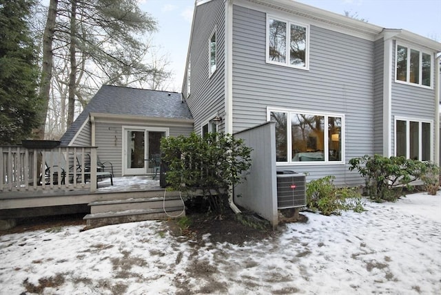 snow covered house with central AC and a deck