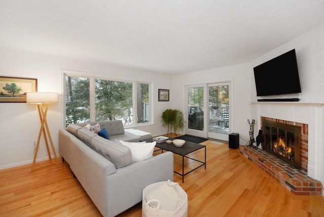 living room with a brick fireplace and light hardwood / wood-style floors