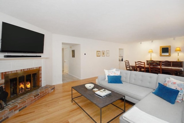 living room with hardwood / wood-style flooring and a brick fireplace