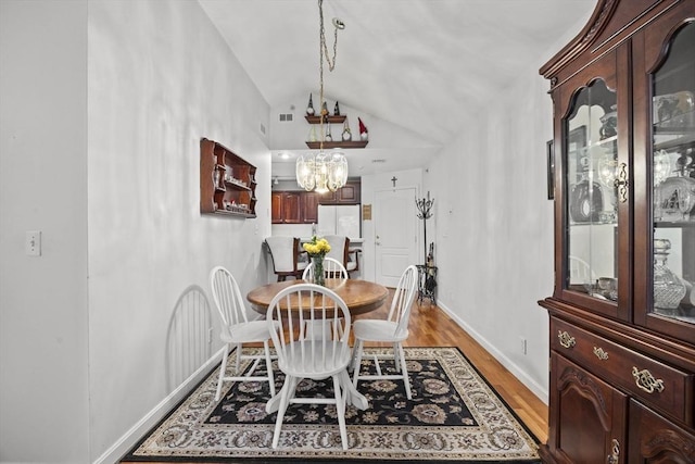 dining space with vaulted ceiling and hardwood / wood-style flooring