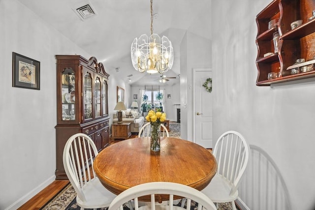 dining area with ceiling fan with notable chandelier, wood-type flooring, and lofted ceiling