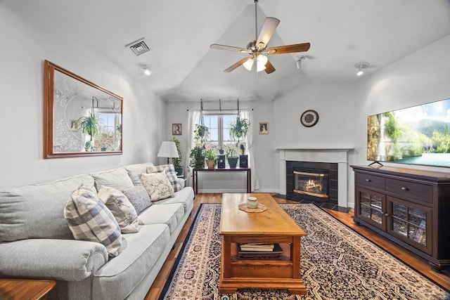 living room with vaulted ceiling, ceiling fan, a fireplace, and wood-type flooring