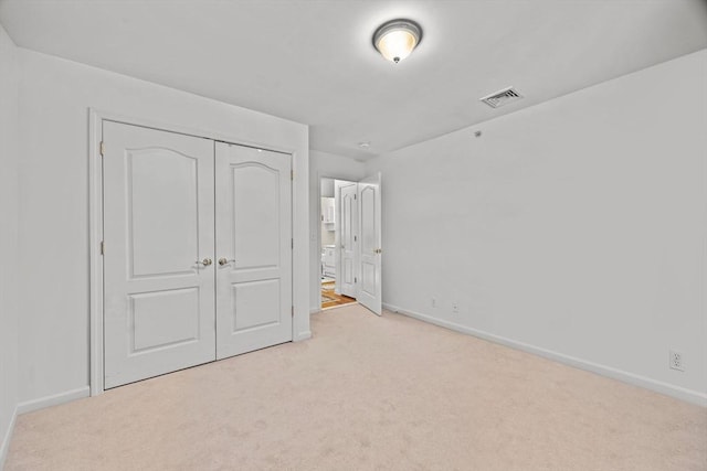 unfurnished bedroom with a closet and light carpet