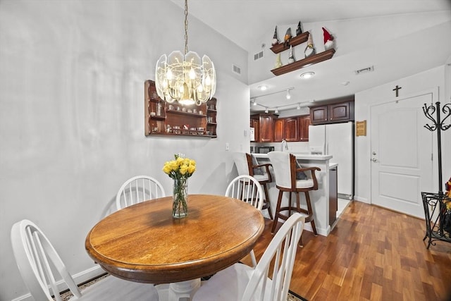 dining area featuring hardwood / wood-style flooring, high vaulted ceiling, and a chandelier