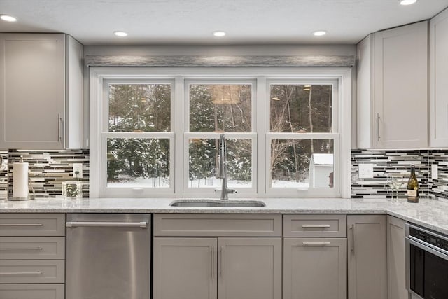 kitchen featuring sink, stainless steel appliances, light stone counters, and gray cabinets