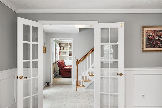 interior space with french doors, ornamental molding, and light tile patterned floors