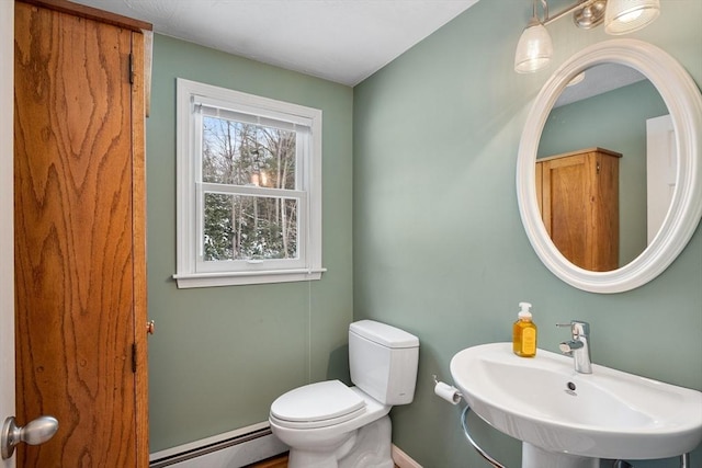 bathroom featuring toilet, baseboard heating, and sink