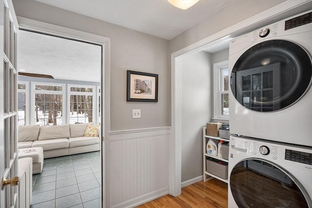 laundry area featuring light hardwood / wood-style floors, a wealth of natural light, and stacked washer and dryer