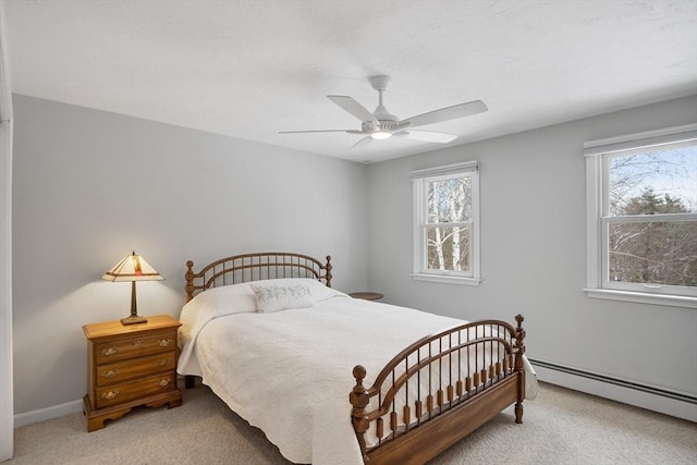 bedroom with multiple windows, baseboard heating, ceiling fan, and carpet