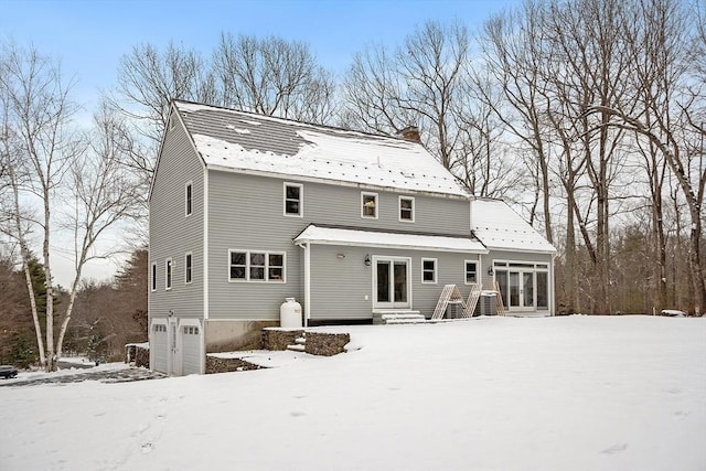 snow covered back of property with a garage