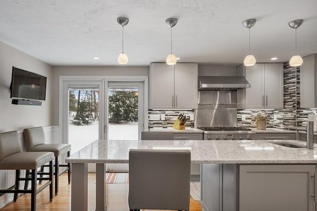 kitchen with sink, decorative light fixtures, light stone counters, and gray cabinets