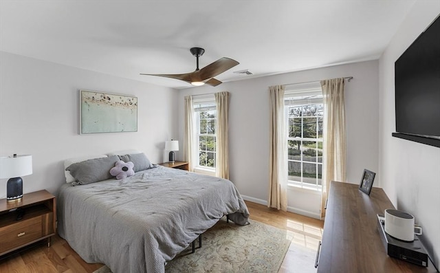 bedroom featuring baseboards, light wood finished floors, ceiling fan, and visible vents