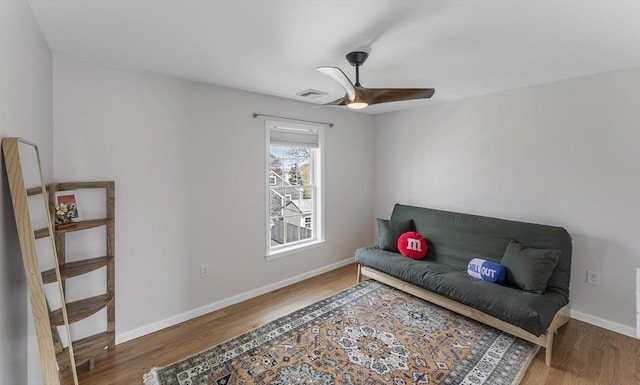 living area with baseboards, a ceiling fan, wood finished floors, and visible vents
