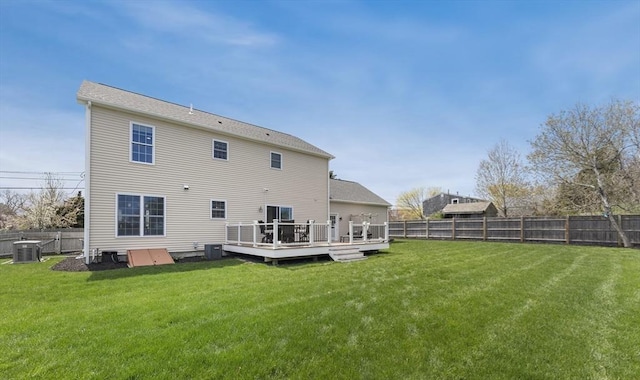 rear view of property with a fenced backyard, a wooden deck, a lawn, and central AC