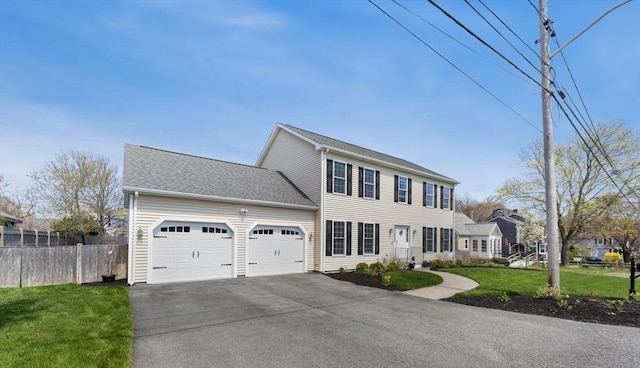 colonial home featuring a garage, fence, a front lawn, and aphalt driveway