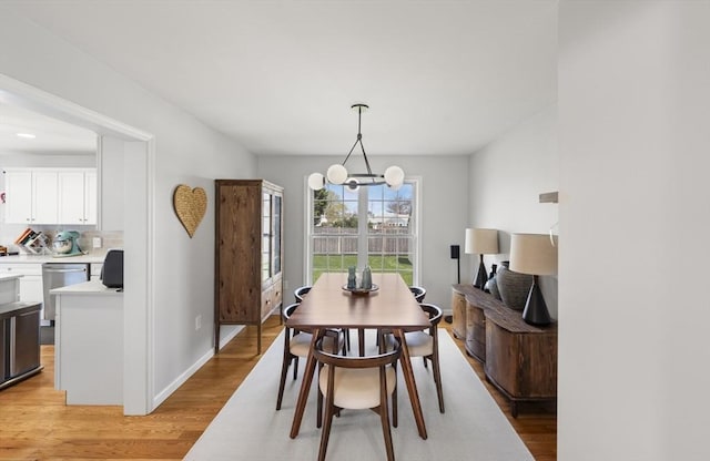 dining area featuring light wood-type flooring, baseboards, and an inviting chandelier