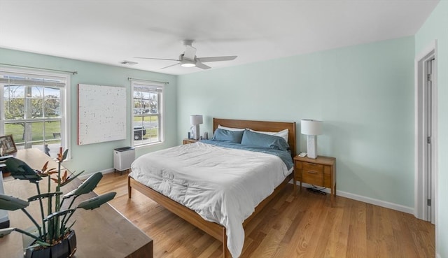 bedroom with baseboards, visible vents, ceiling fan, and light wood-style floors