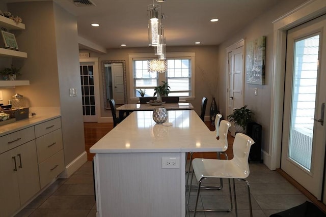 142 Vinal St, Revere, MA 02151 - kitchen featuring a center island, a kitchen bar, light tile patterned flooring, light countertops, and white cabinetry