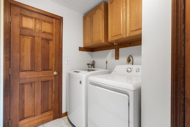 clothes washing area with light tile patterned floors, cabinet space, and washing machine and dryer