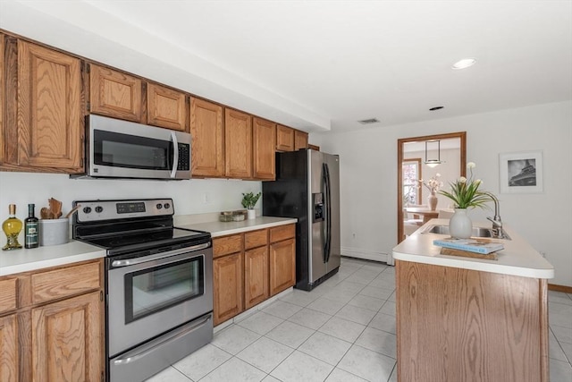kitchen featuring light tile patterned floors, a sink, appliances with stainless steel finishes, light countertops, and brown cabinetry