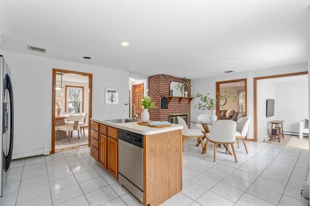 kitchen featuring a baseboard heating unit, a sink, a brick fireplace, light countertops, and stainless steel dishwasher