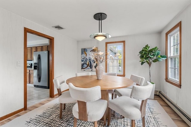 dining area featuring a wealth of natural light, visible vents, a baseboard heating unit, and light wood finished floors