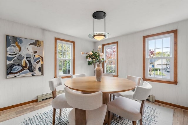 dining area featuring wood finished floors, baseboard heating, a baseboard heating unit, and baseboards