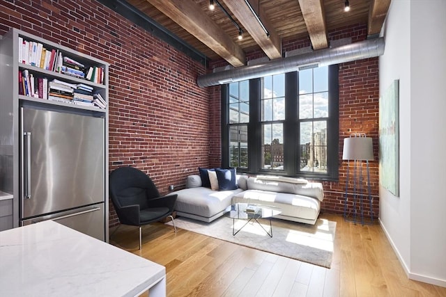 sitting room featuring brick wall, wooden ceiling, light wood-type flooring, and beamed ceiling