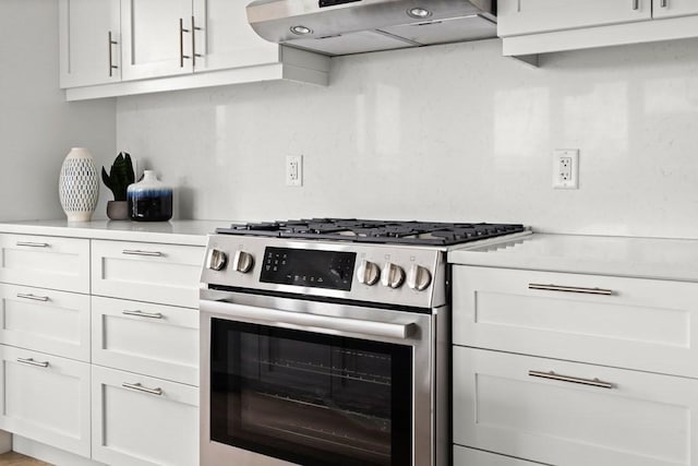 kitchen featuring light countertops, stainless steel range with gas stovetop, white cabinets, and under cabinet range hood