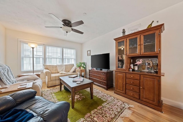 living room with light wood finished floors, baseboards, and a ceiling fan